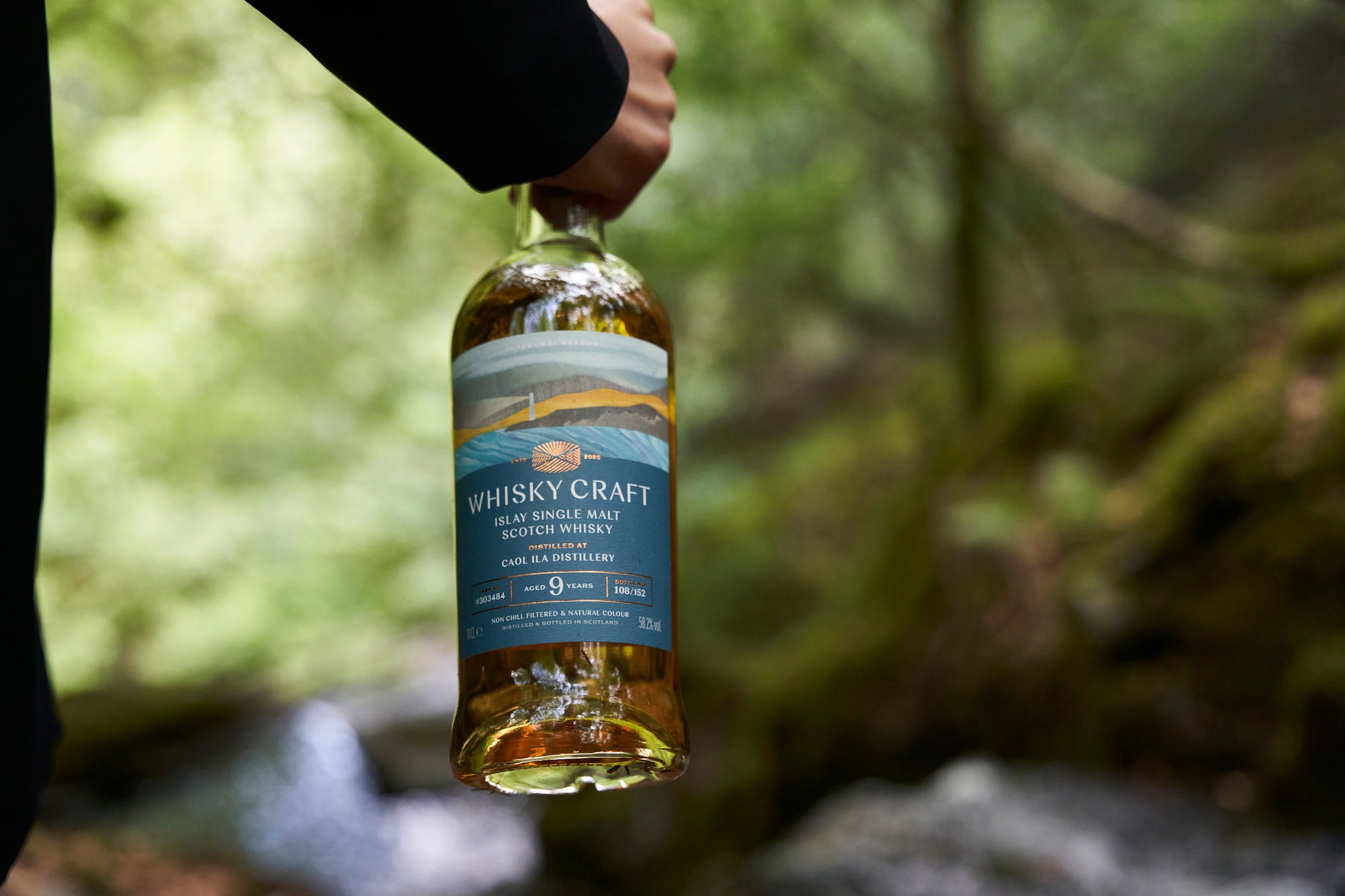 Close-up of someone carrying a bottle of Islay whisky from the neck