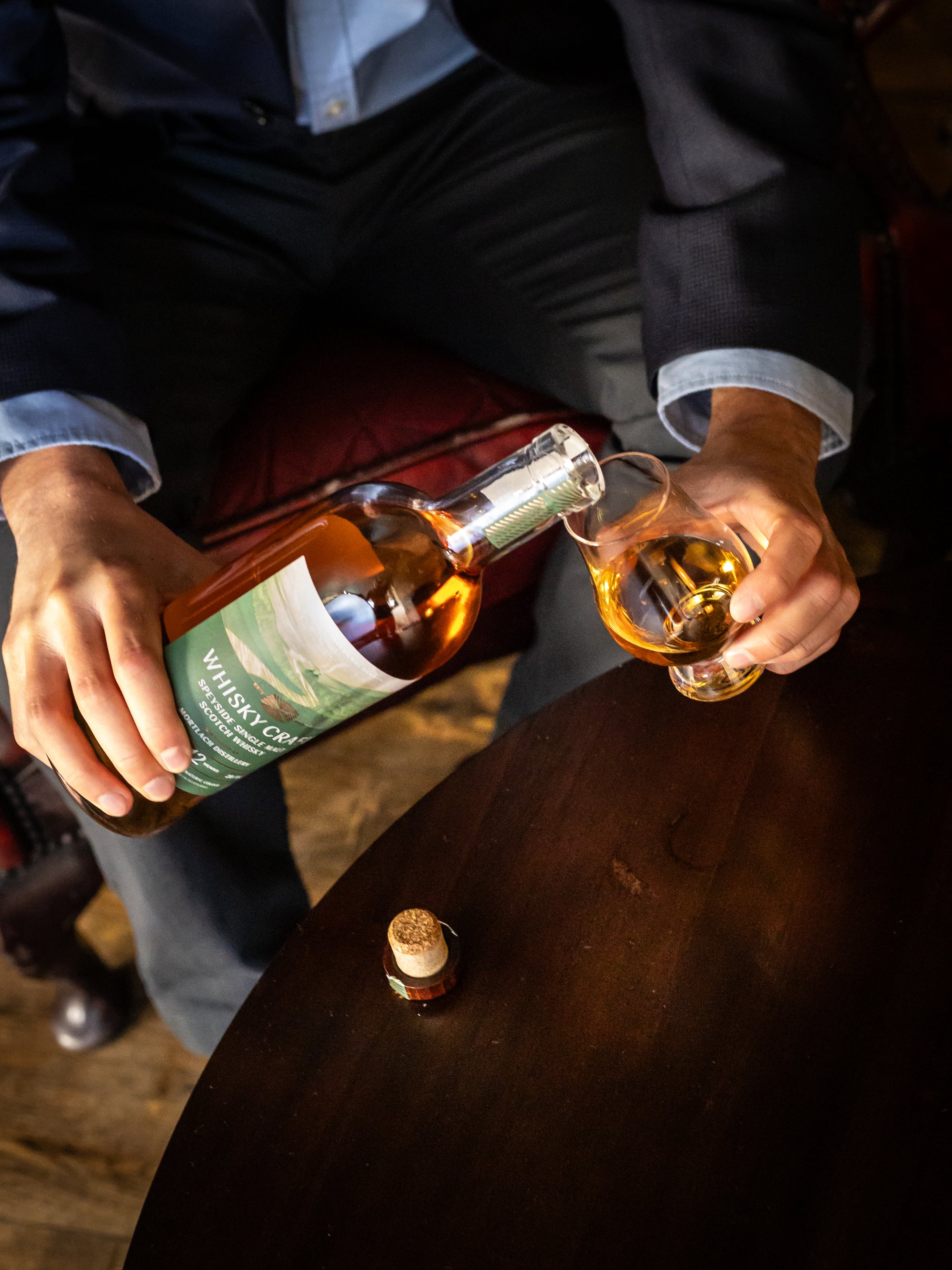Pouring a bottle of whisky into a glass, looking classy